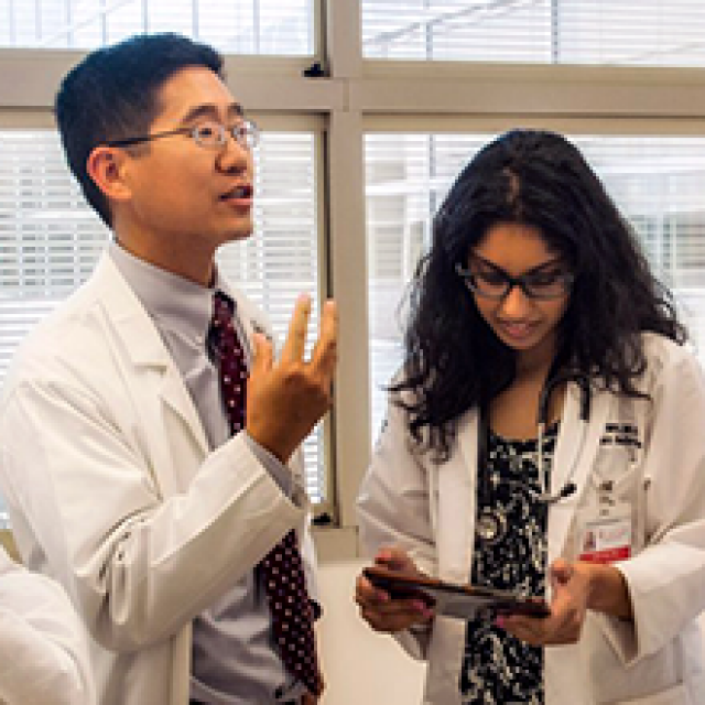 Two graduate students talking to each other, wearing lab coats