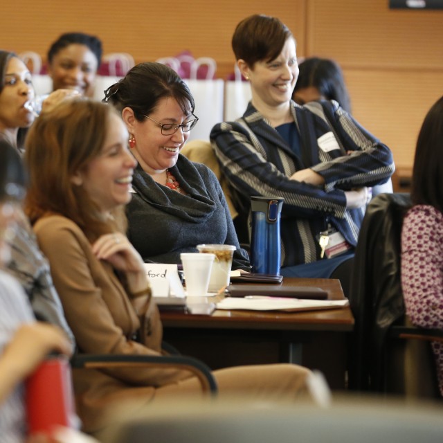 Faculty members in the audience of a talk, laughing